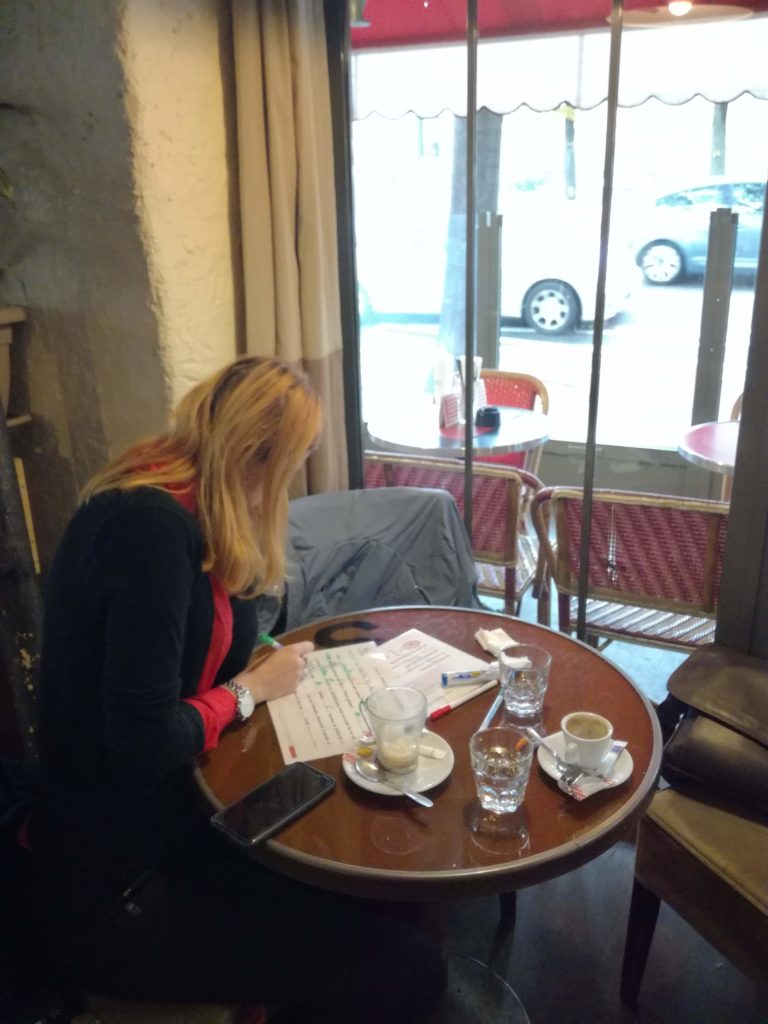 Photo d'un personne attablée au café en train d'écrire