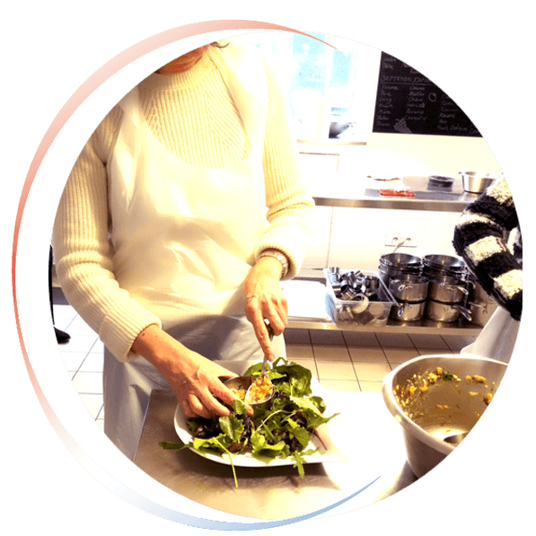Vignette ronde d'une femme dressant une assiette dans une cuisine professionnelle